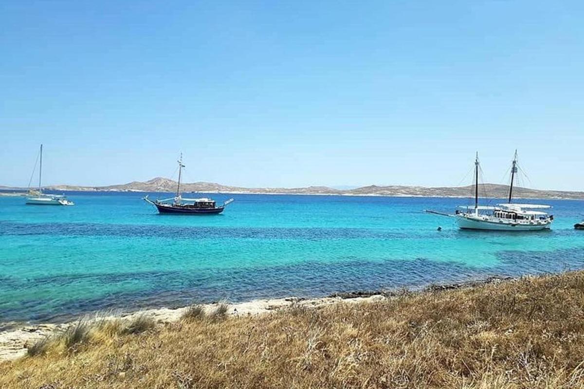 three boats sitting in the water near a beach