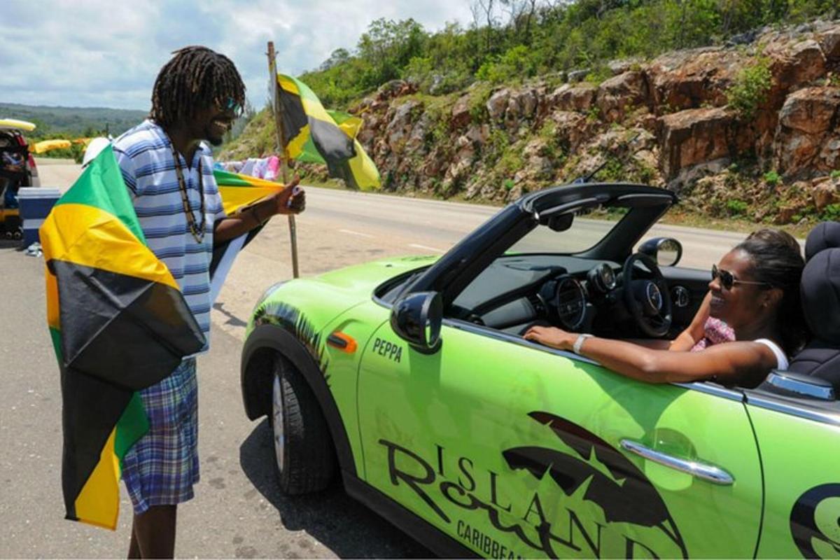 Un hombre está parado junto a un coche verde.