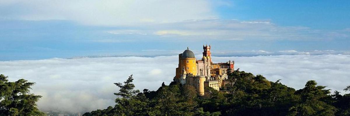 un castillo en la cima de una colina sobre las nubes