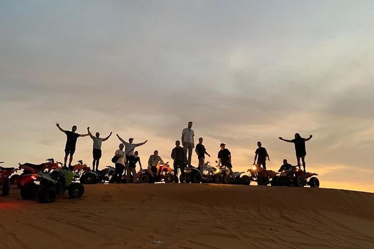 un grup de persones dretes al cim d'un turó de sorra