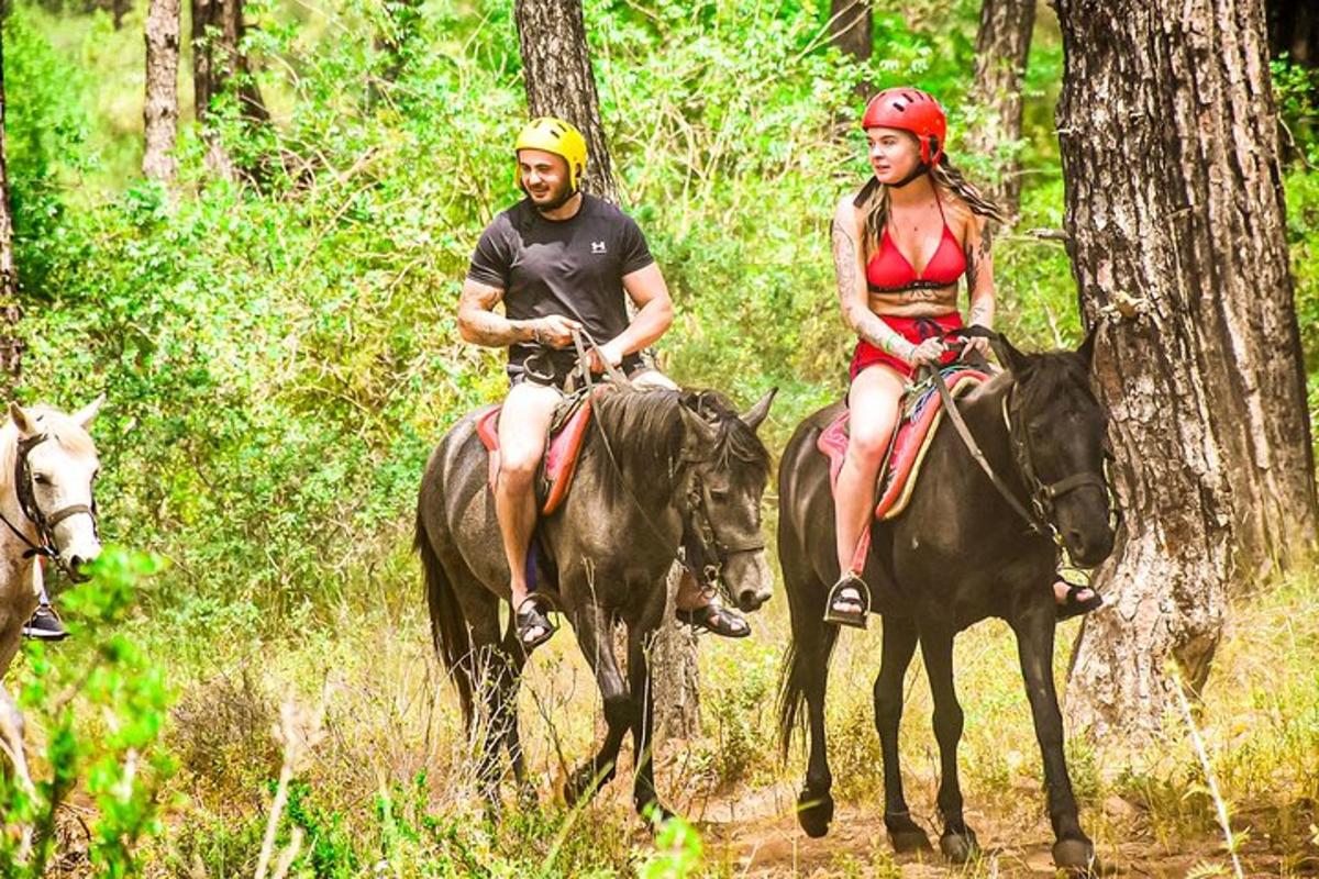 a man and a woman riding horses in the woods