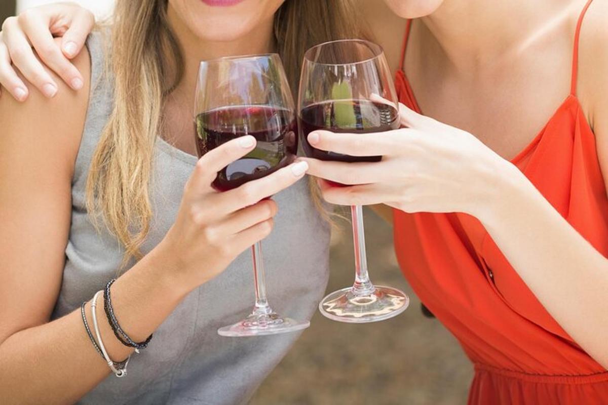 două femei țin pahare de vin roșu