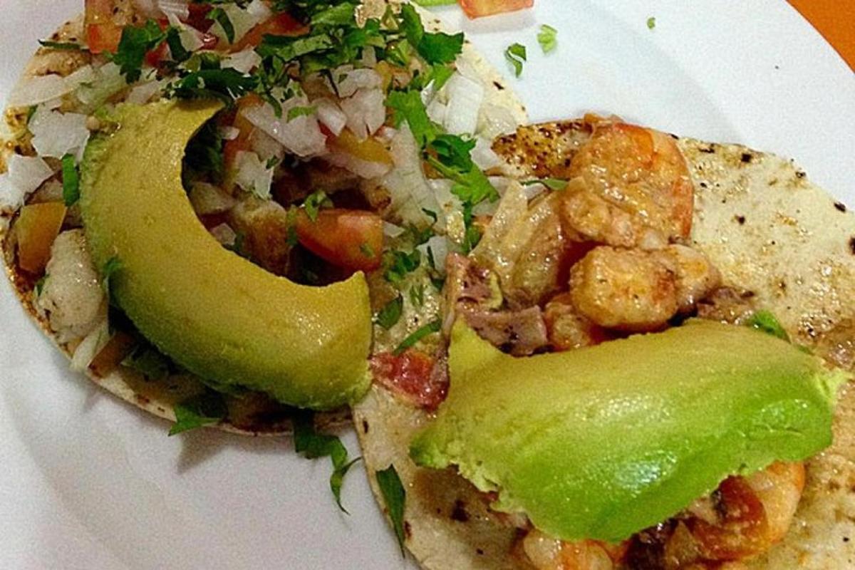 un piatto bianco con un panino con avocado e verdure