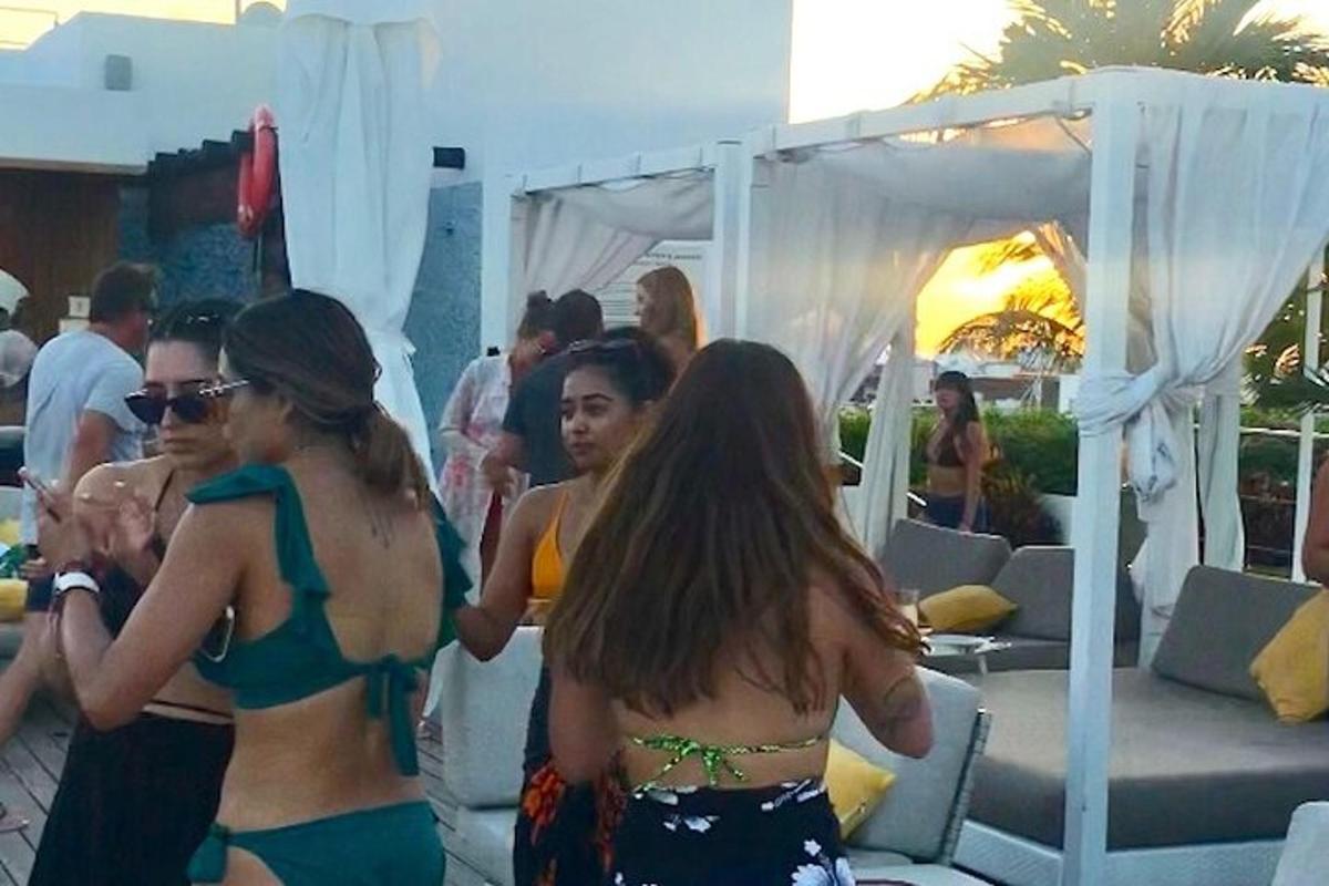 Hópur kvenna í bikiníum standa undir tjaldhimni