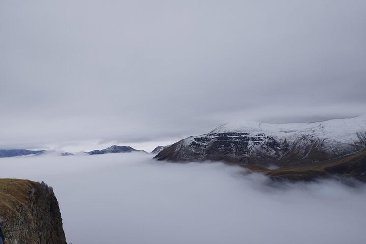 Un hombre parado en la cima de una montaña en las nubes.