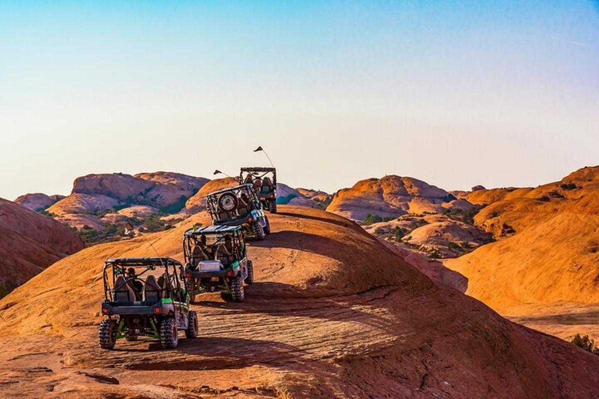 a group of four jeeps driving down a hill
