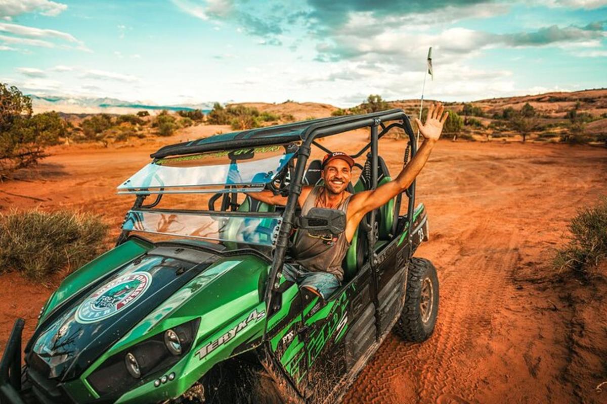 a man waving from the back of a green jeep