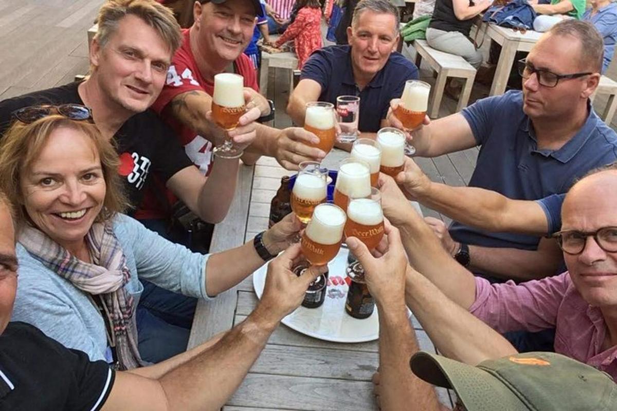 skupina lidí sedících kolem stolu a pijících pivo