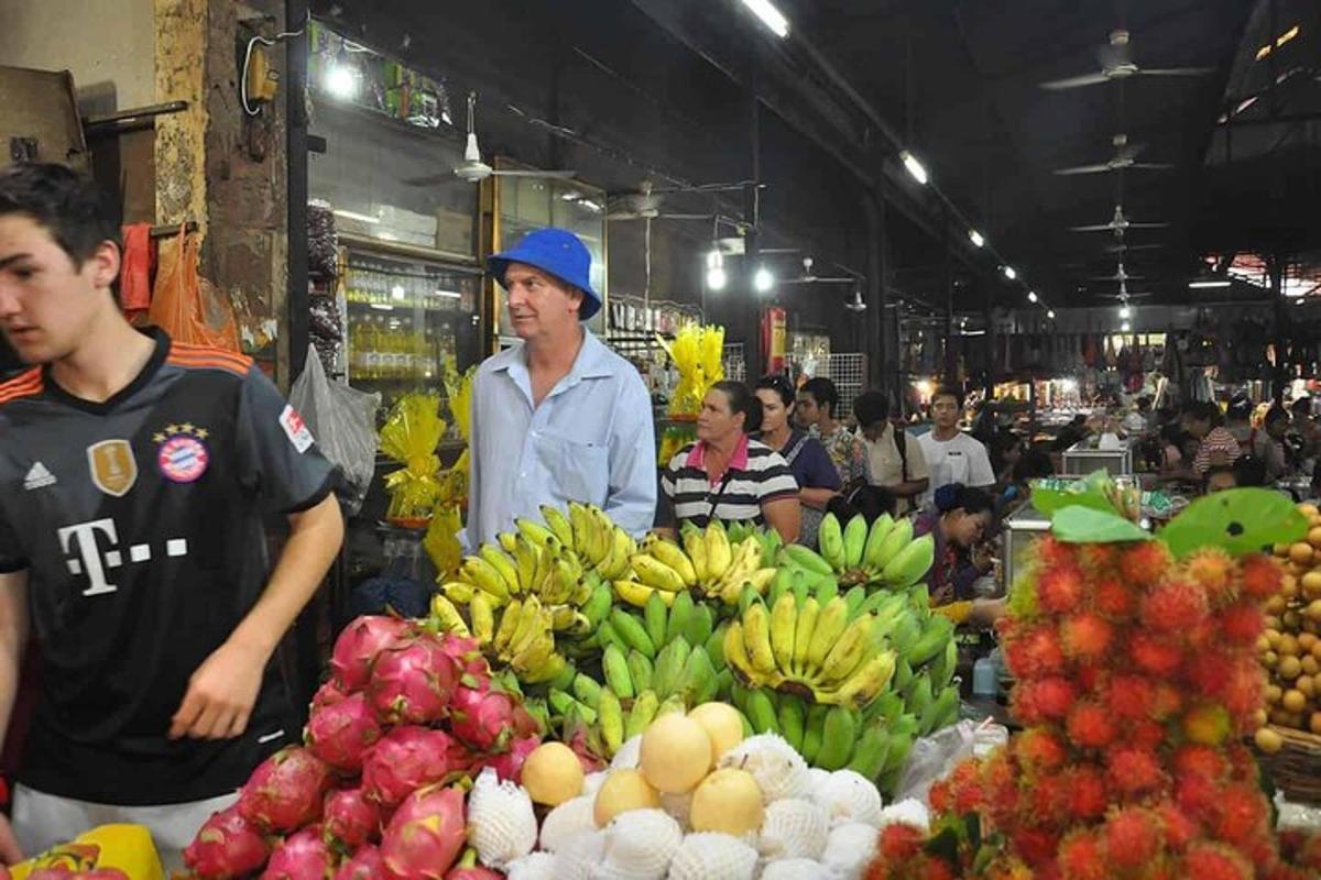 a group of people standing in a market with fruit