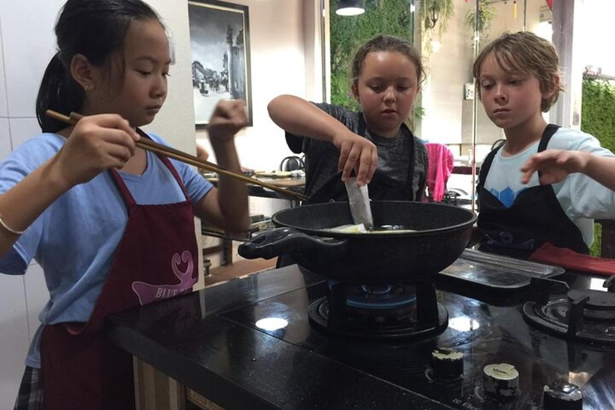 a group of children cooking food in a wok
