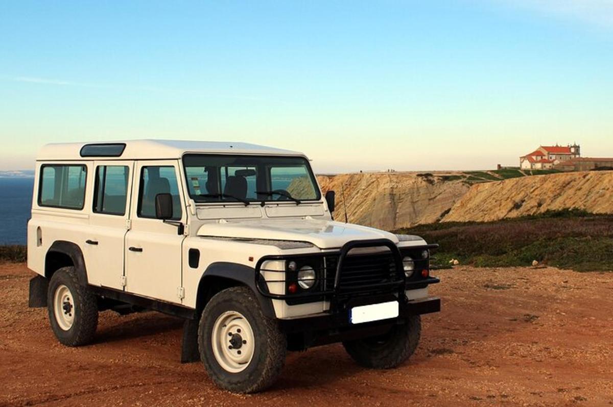 una jeep bianca parcheggiata in cima a un campo sterrato