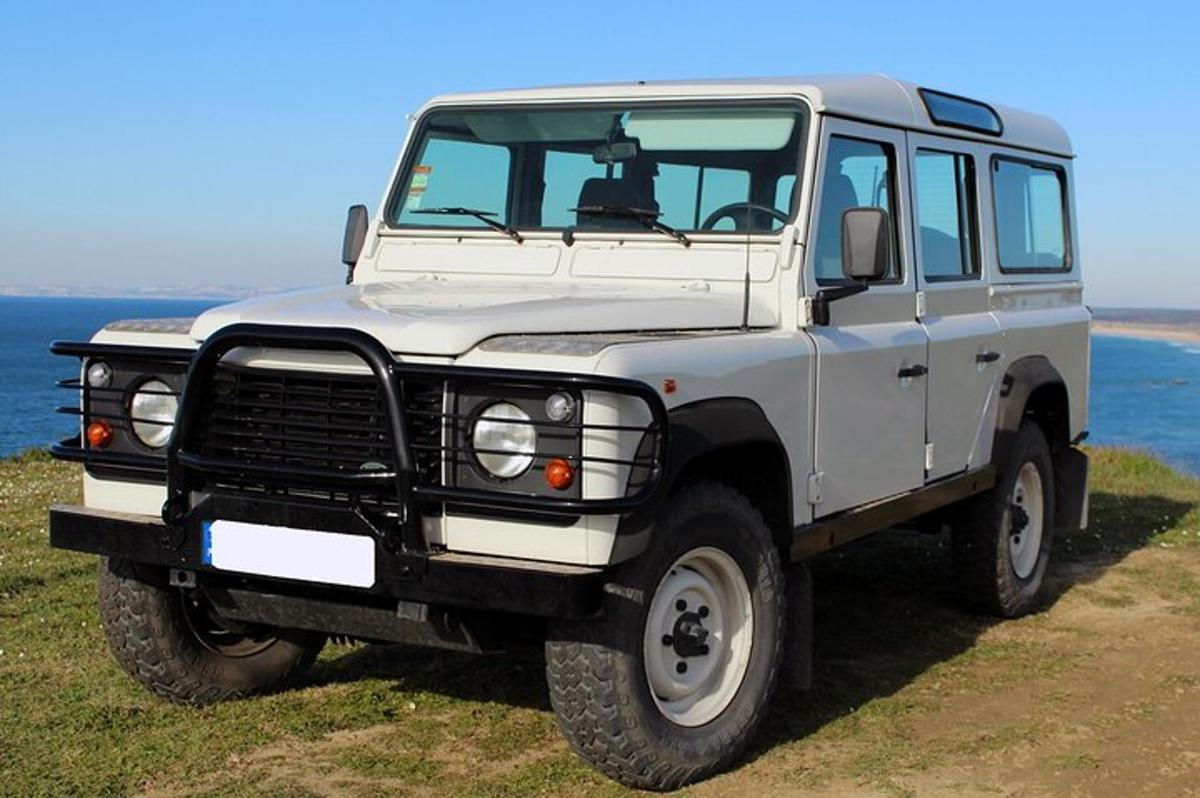 una jeep bianca parcheggiata sull'erba vicino all'oceano