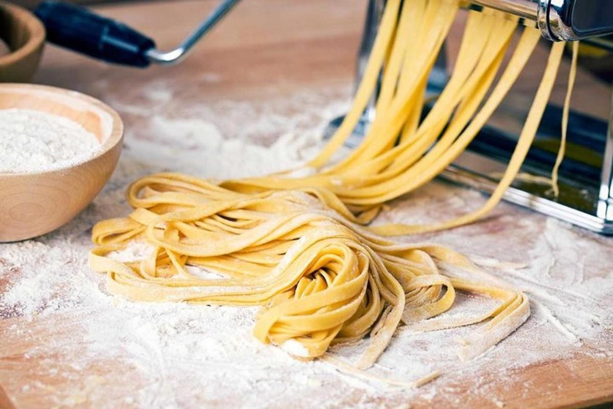 una pila di pasta su un bancone con una ciotola di farina