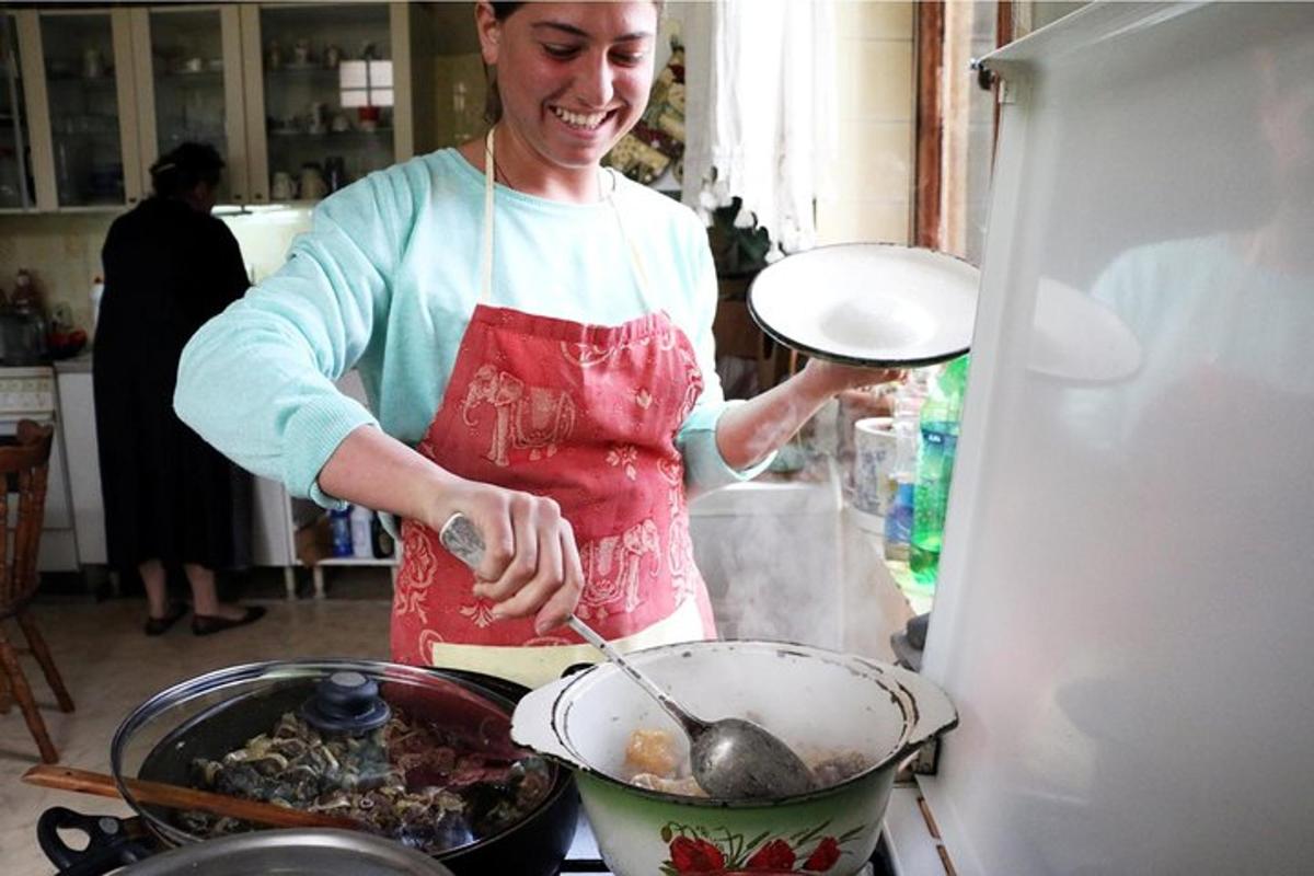 uma mulher na cozinha preparando comida em uma panela