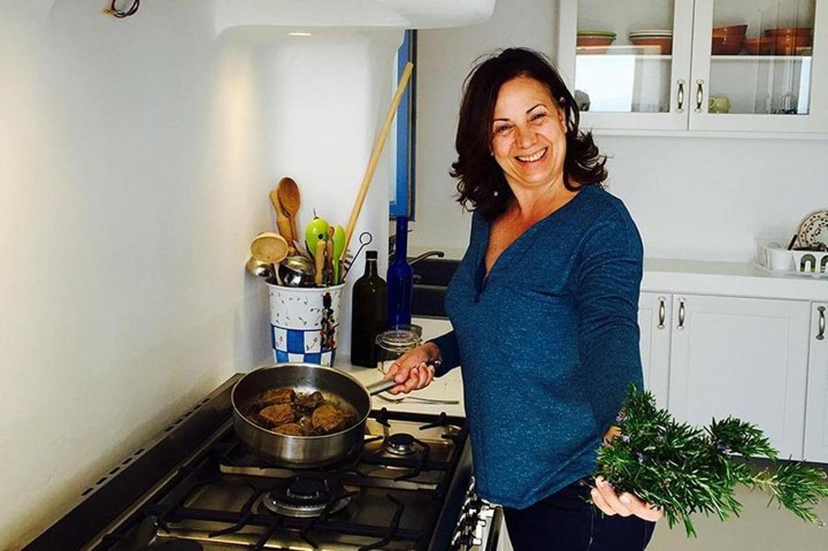 Una mujer cocinando comida en una sartén en una cocina.