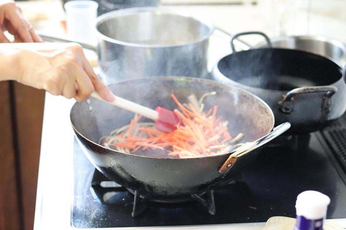 uma pessoa mexendo uma wok com uma colher de pau