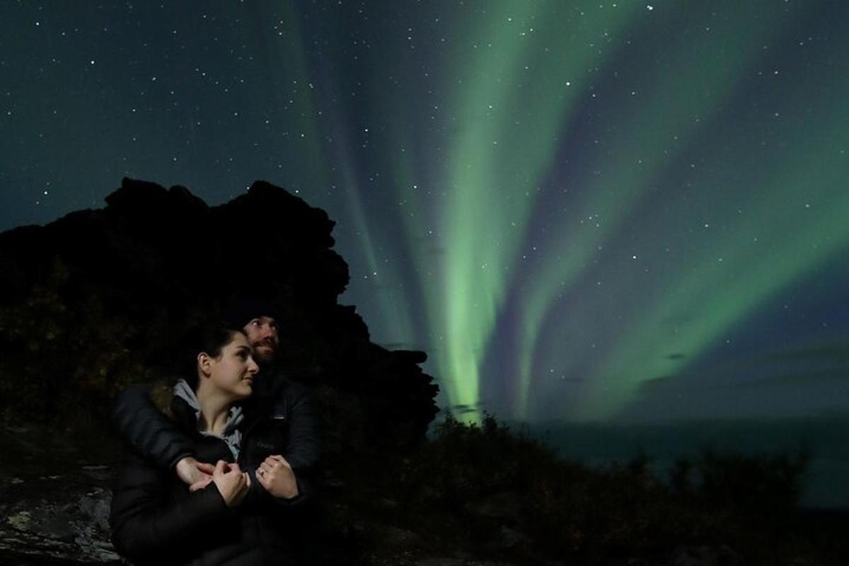 duas pessoas em pé sob a aurora boreal no céu