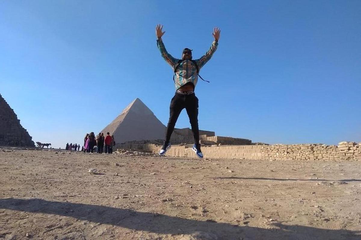 mies hyppää ilmaan pyramidien edessä