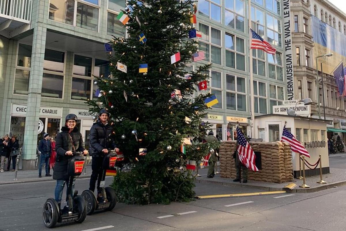 duas pessoas andando de segway em frente a uma árvore de natal