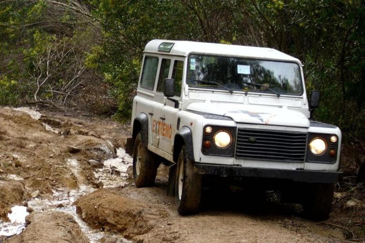 um jipe branco dirigindo por uma estrada lamacenta