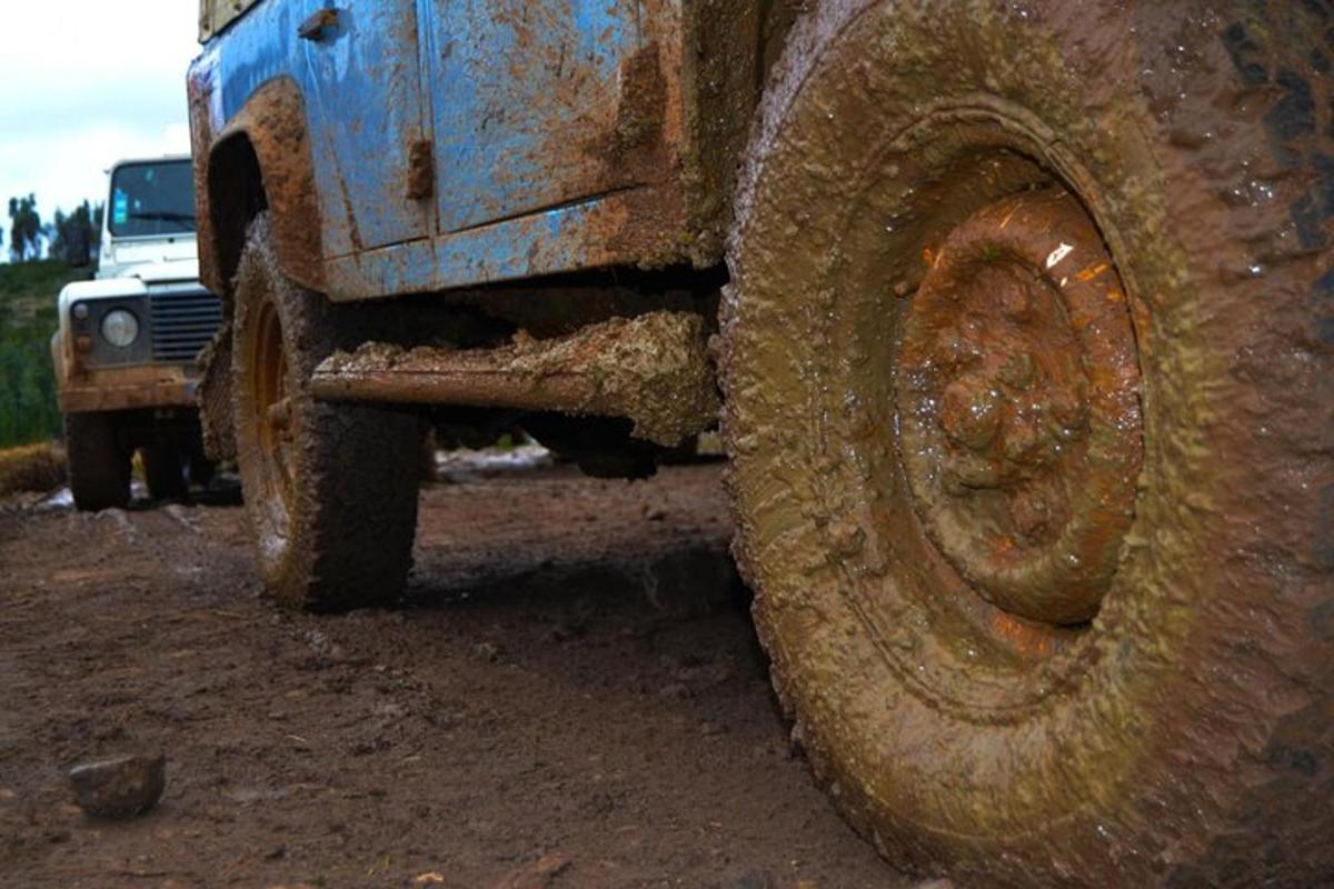 um grande caminhão lamacento estacionado em uma estrada de terra