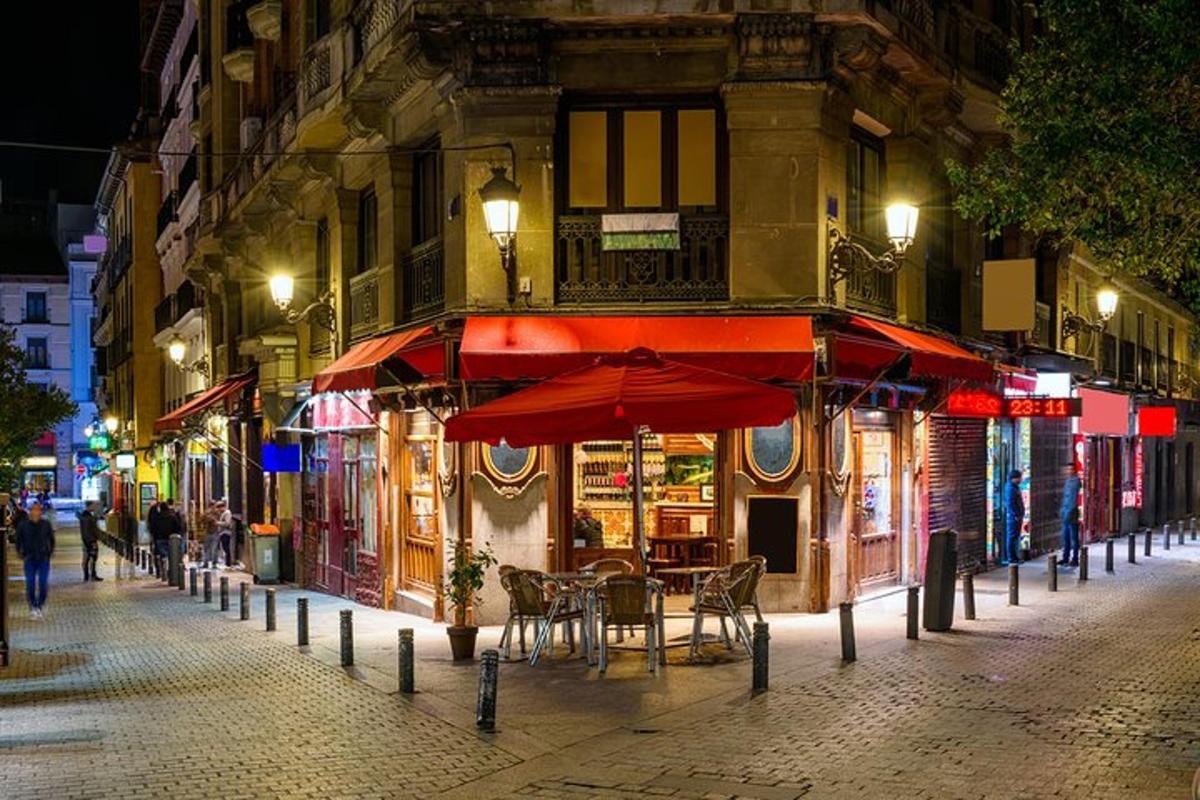 Una calle con un café con mesas y sombrillas por la noche.