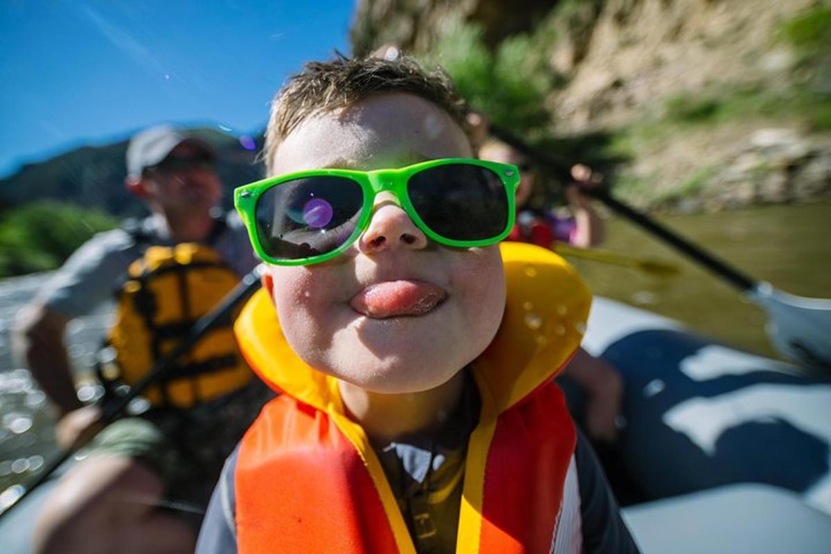 a young boy wearing green goggles and sticking his tongue