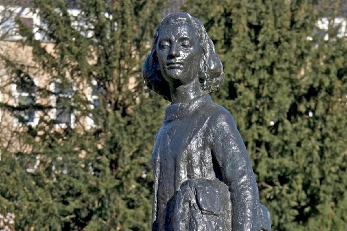 eine Statue einer Frau, die vor Bäumen steht