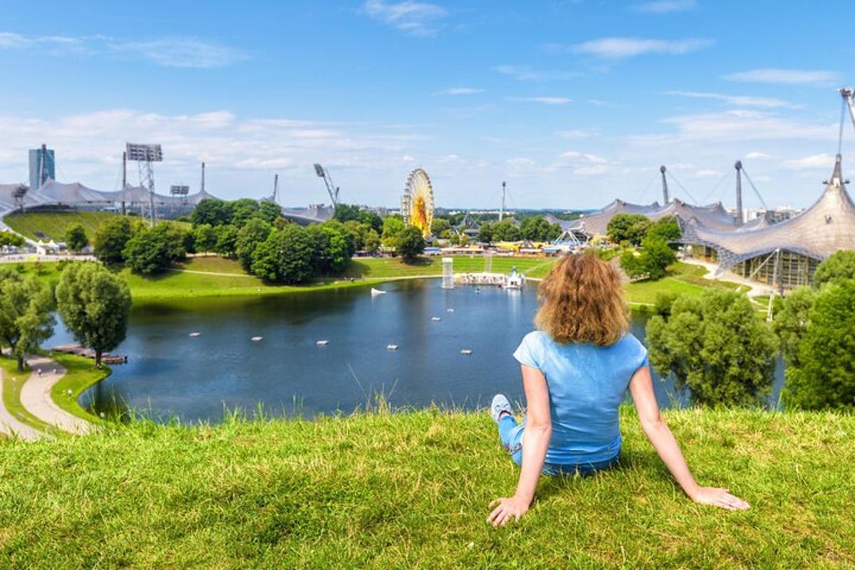 a woman sitting on the grass looking at a lake
