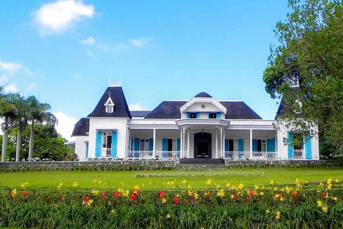 sebuah rumah putih besar dengan bunga di depannya