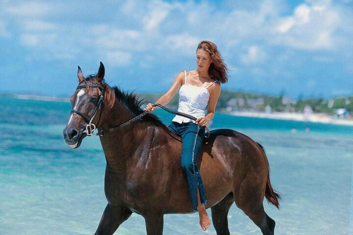 žena jedoucí na koni na pláži