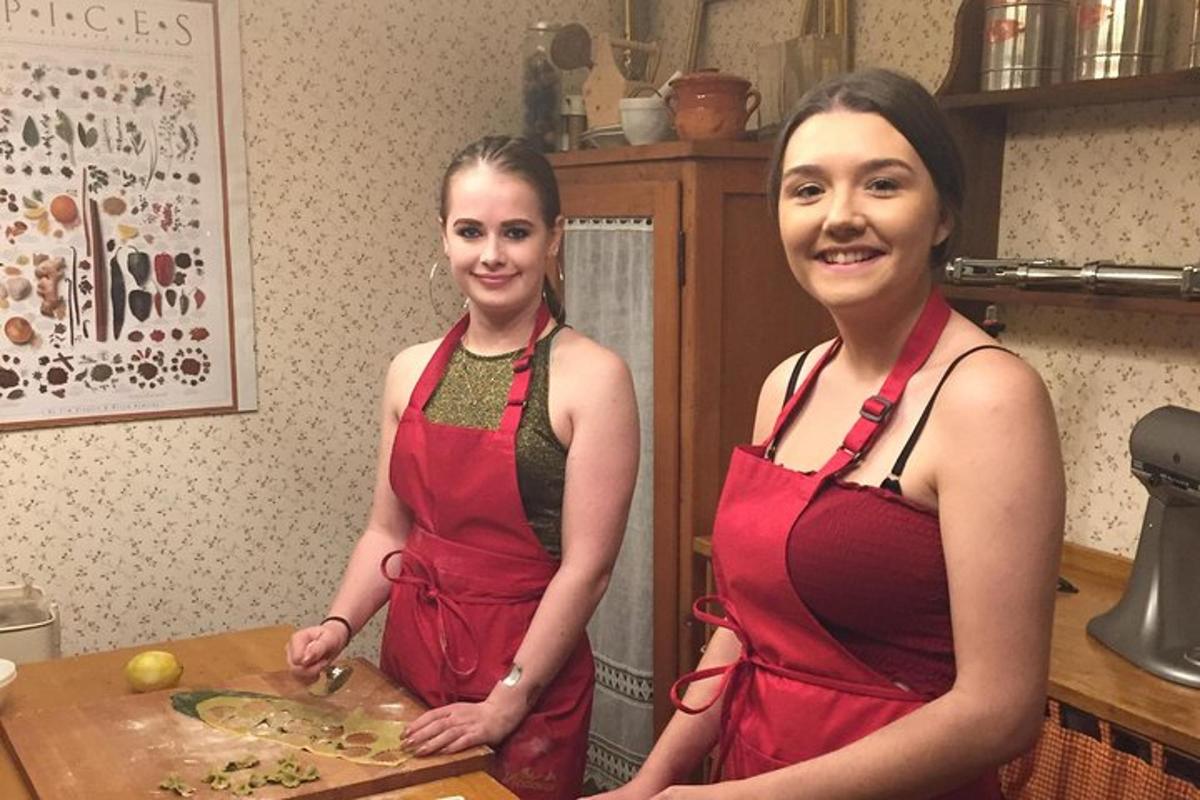 Două femei stau în bucătărie pregătind mâncare