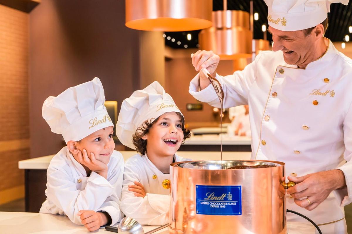 a man and two children wearing chefs hats in a kitchen