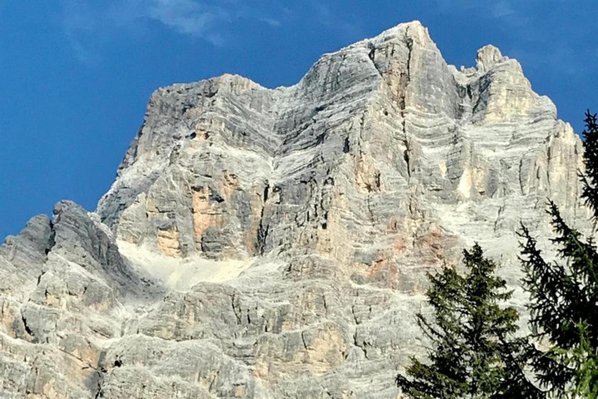 Una gran montaña rocosa con árboles delante.