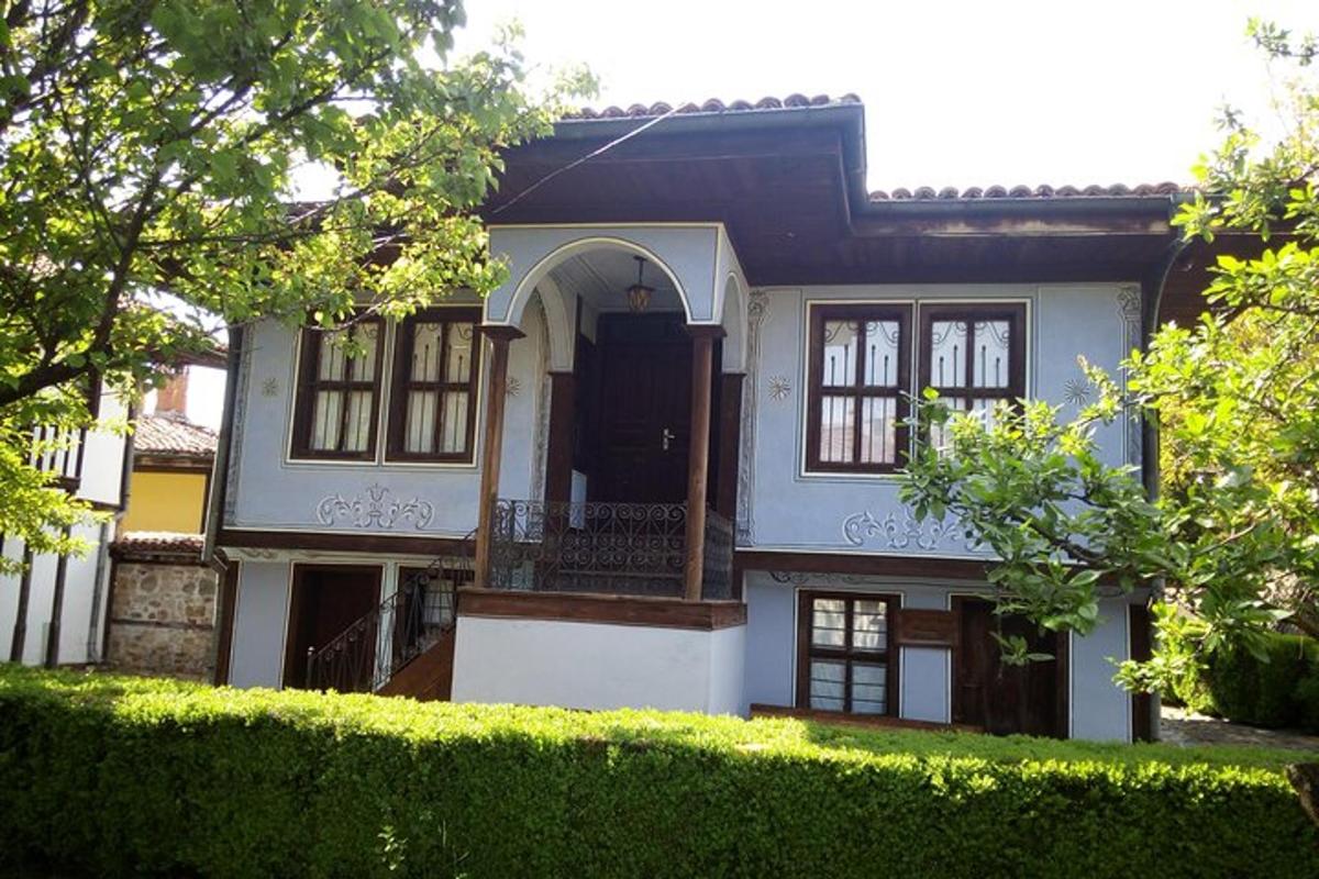 uma casa branca com uma porta preta e uma cerca viva