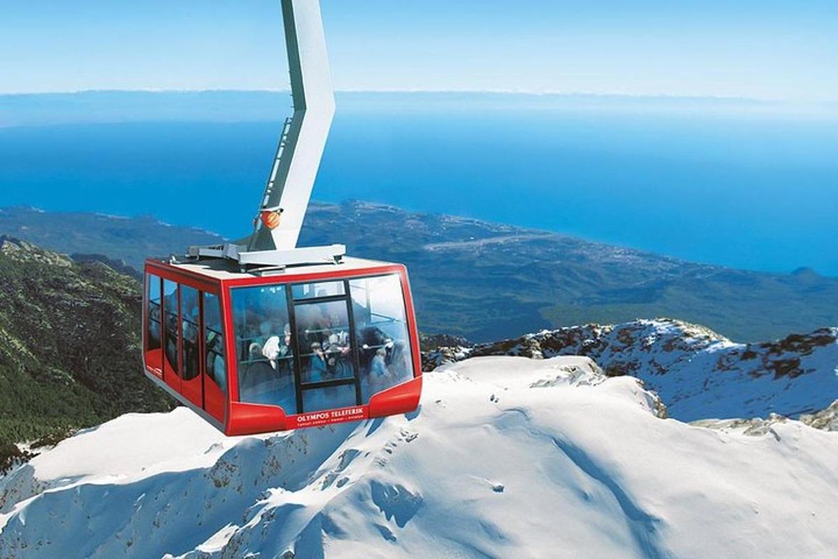 a red ski lift flying over a snow covered mountain