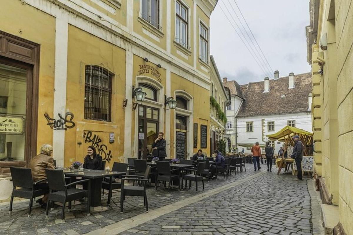 cilvēku grupa, kas sēž pie galdiņiem uz ielas