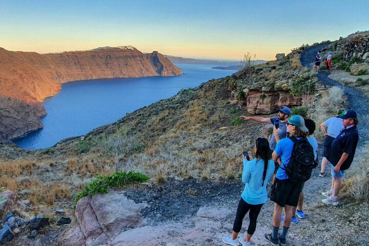 um grupo de pessoas em pé em uma colina olhando para um lago
