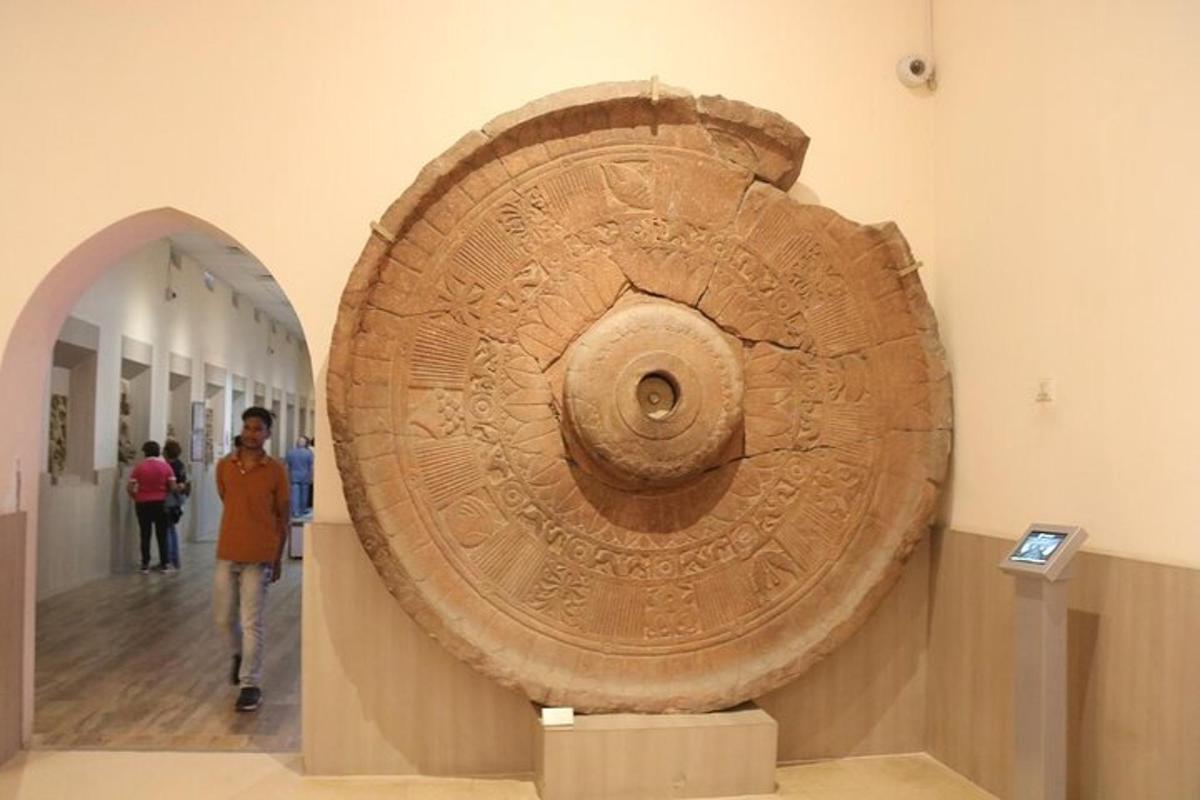 ένα άτομο που περπατάει δίπλα από ένα μεγάλο τεχνούργημα σε ένα μουσείο