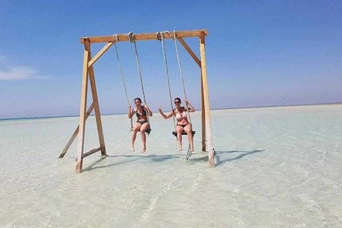Δύο γυναίκες με μαγιό παίζουν σε μια κούνια στην παραλία