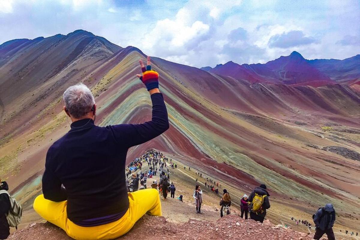 een man die op de grond zit en naar een berg kijkt