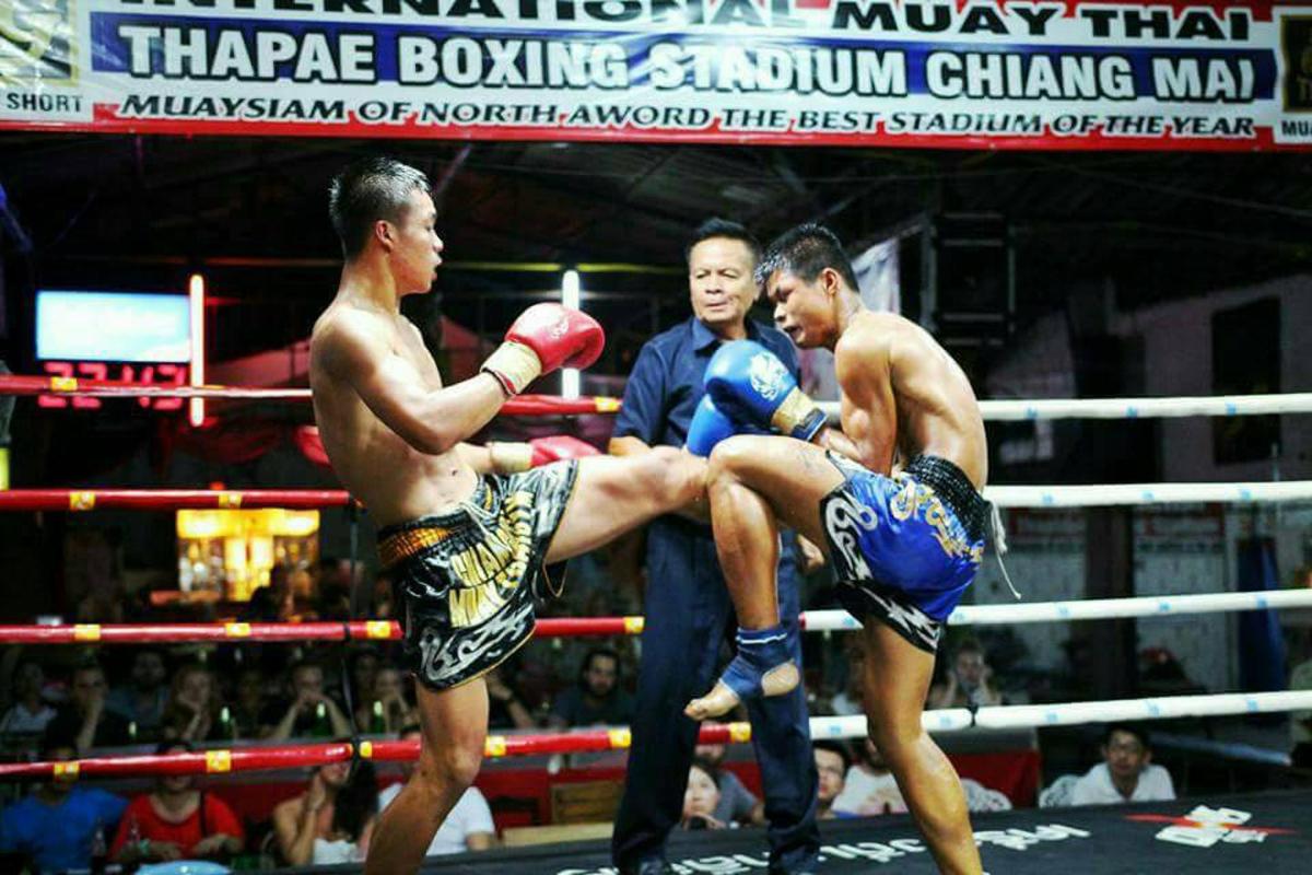 three men in a boxing match in front of a crowd