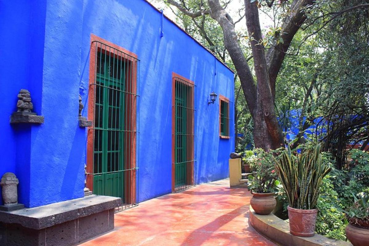 a blue building with green doors in a yard