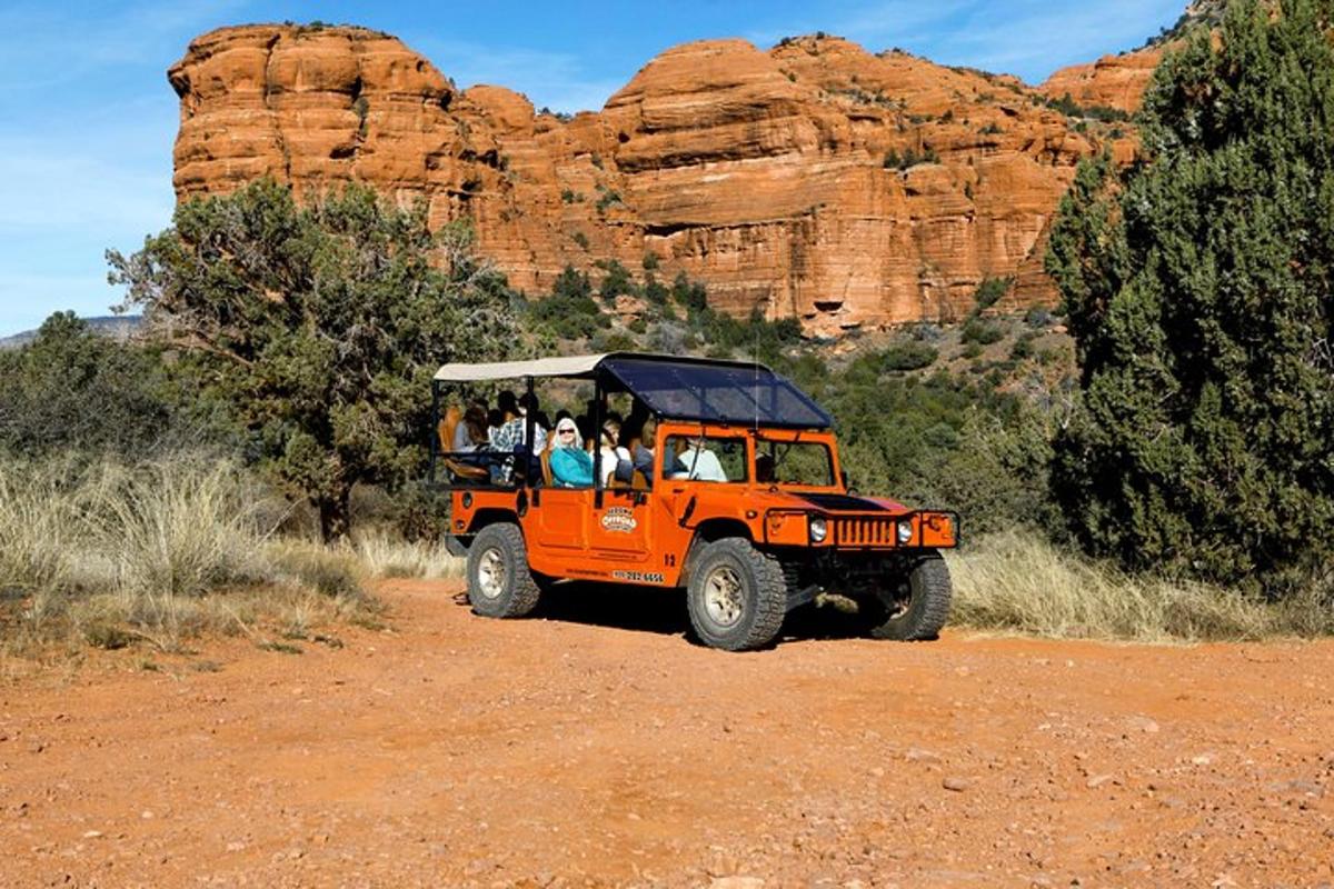 una jeep arancione che percorre una strada sterrata