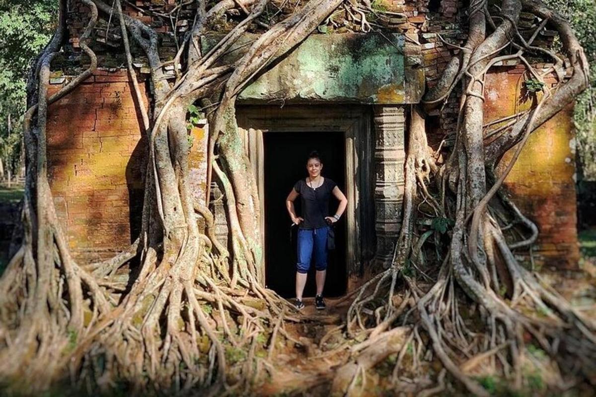 a man standing in the doorway of a building with tree roots