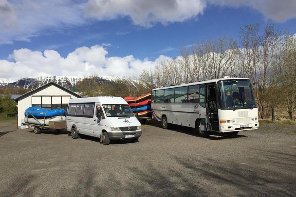 Dos autobuses estacionados en un estacionamiento con un remolque