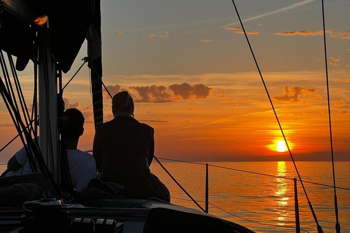 two people sitting on a boat watching the sunset
