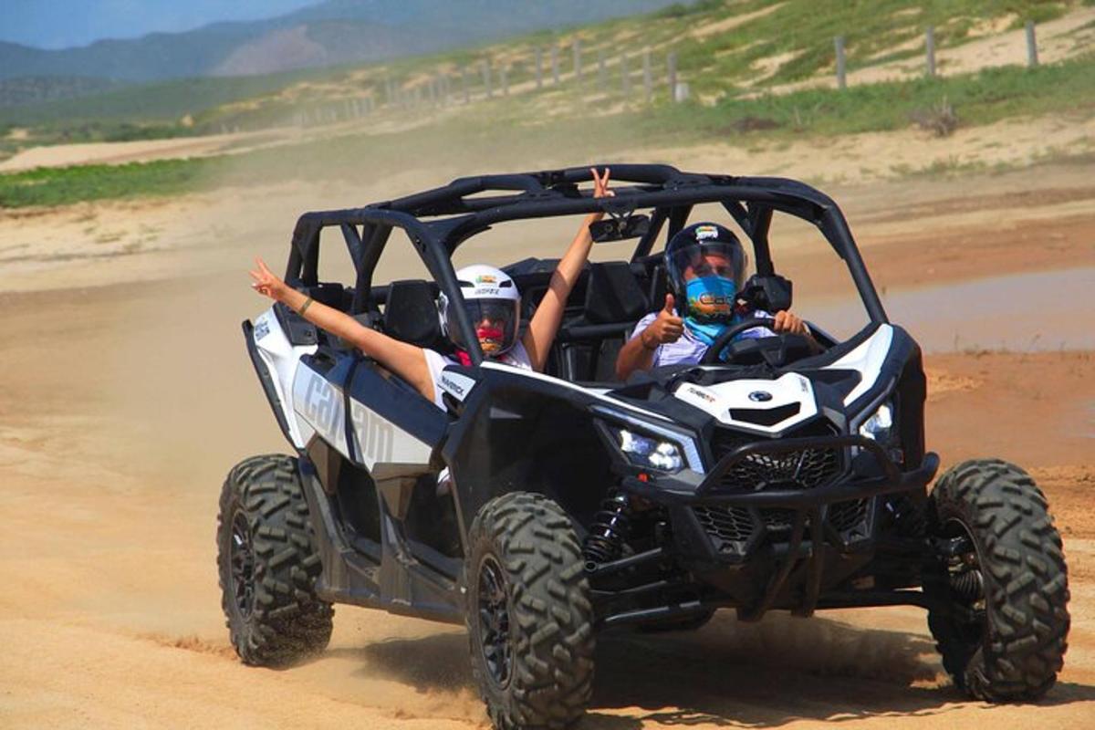 two people riding in a wheeler on the beach