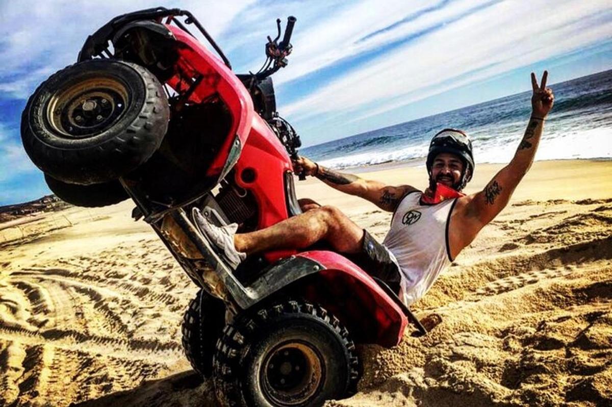 Un hombre está sentado en una moto en la playa.
