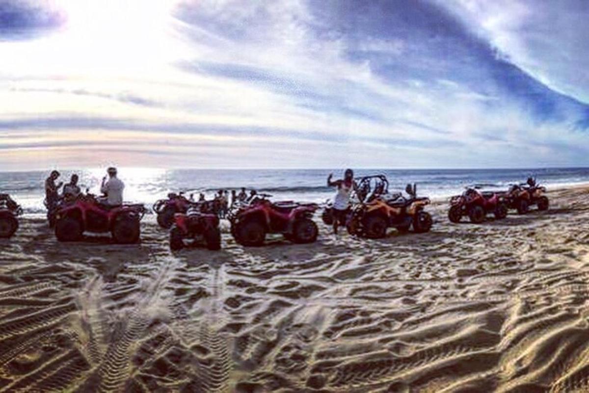 a group of people riding atvs on the beach